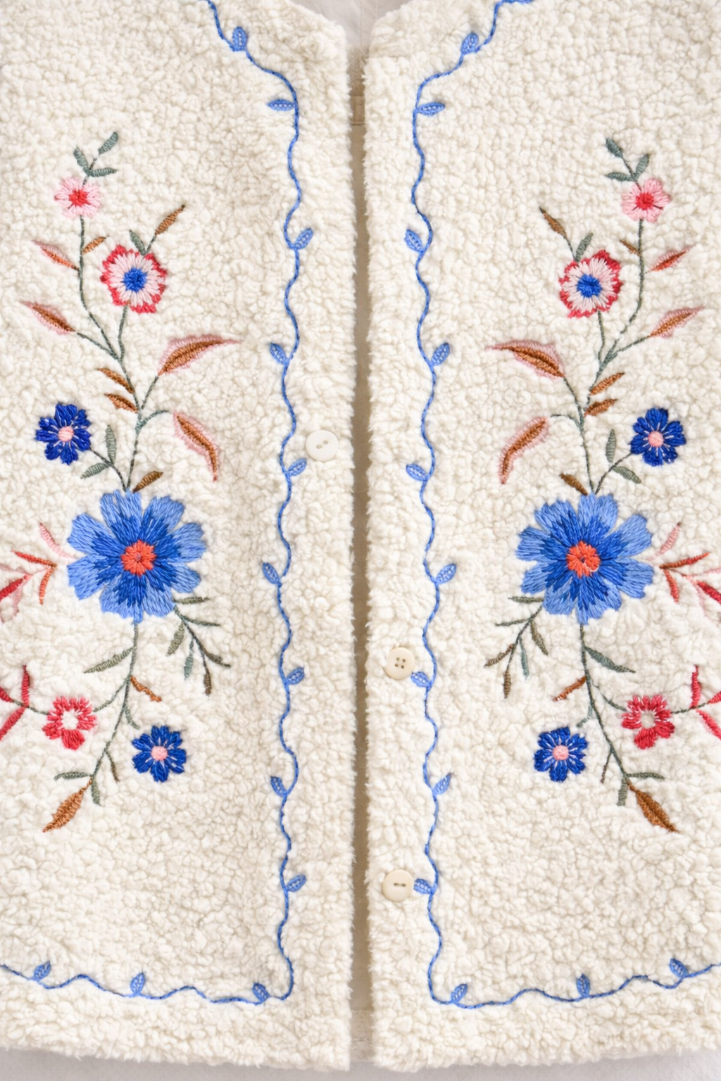 Détail des broderies délicates sur le gilet Julia en sherpa écru