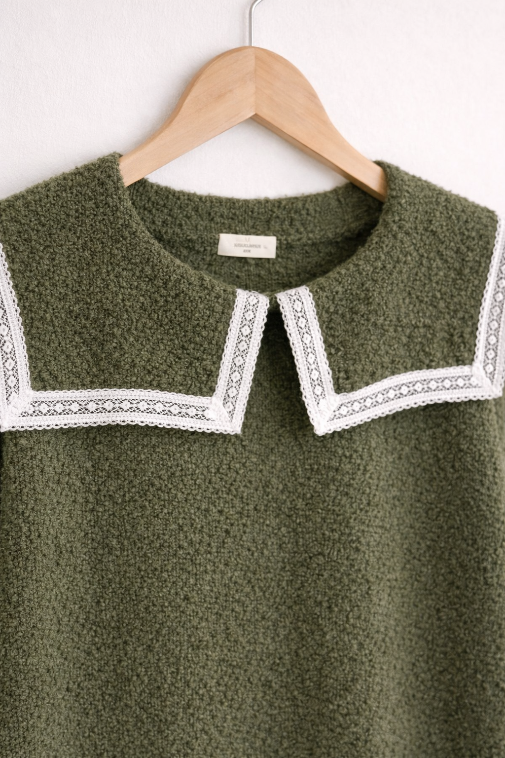 Détail des manches boutonnées avec boutons dorés du pull Clothilde vert